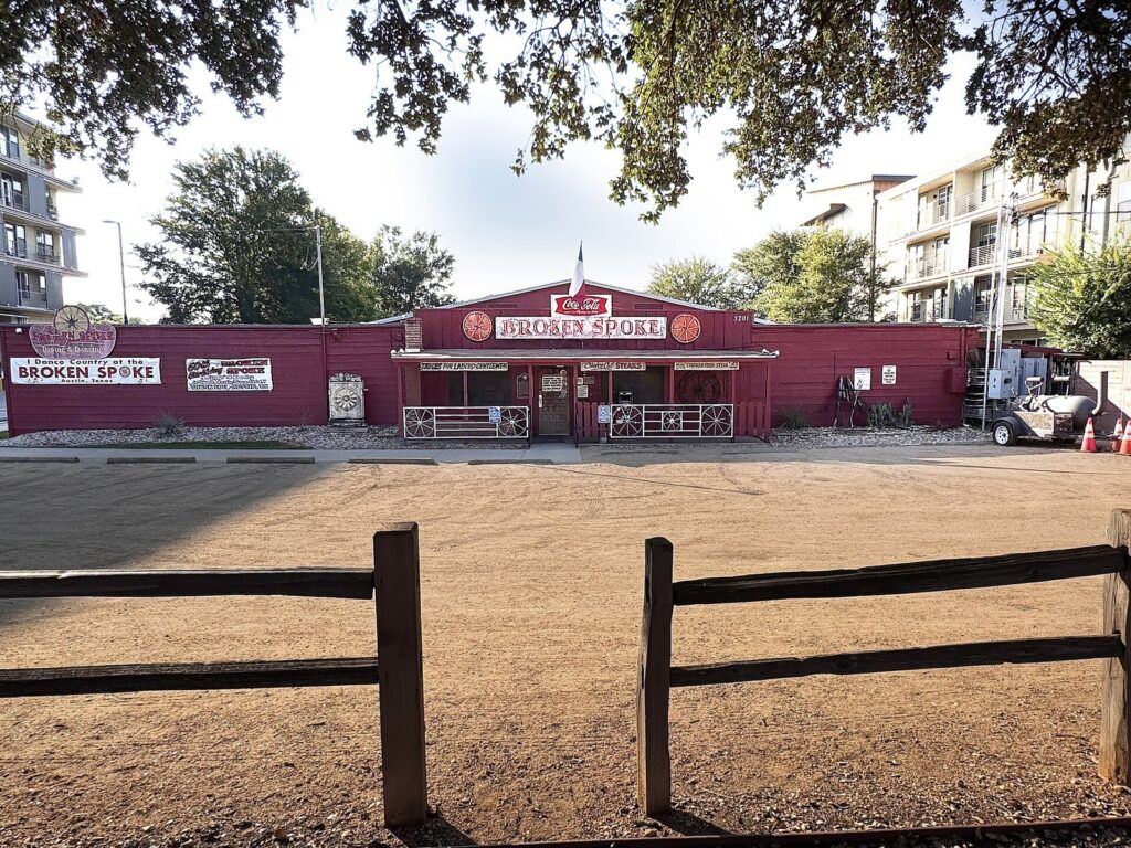 The red wooden front of the Broken Spoke dance hall on South Lamar Boulevard, with its sign and a wooden fence in the foreground