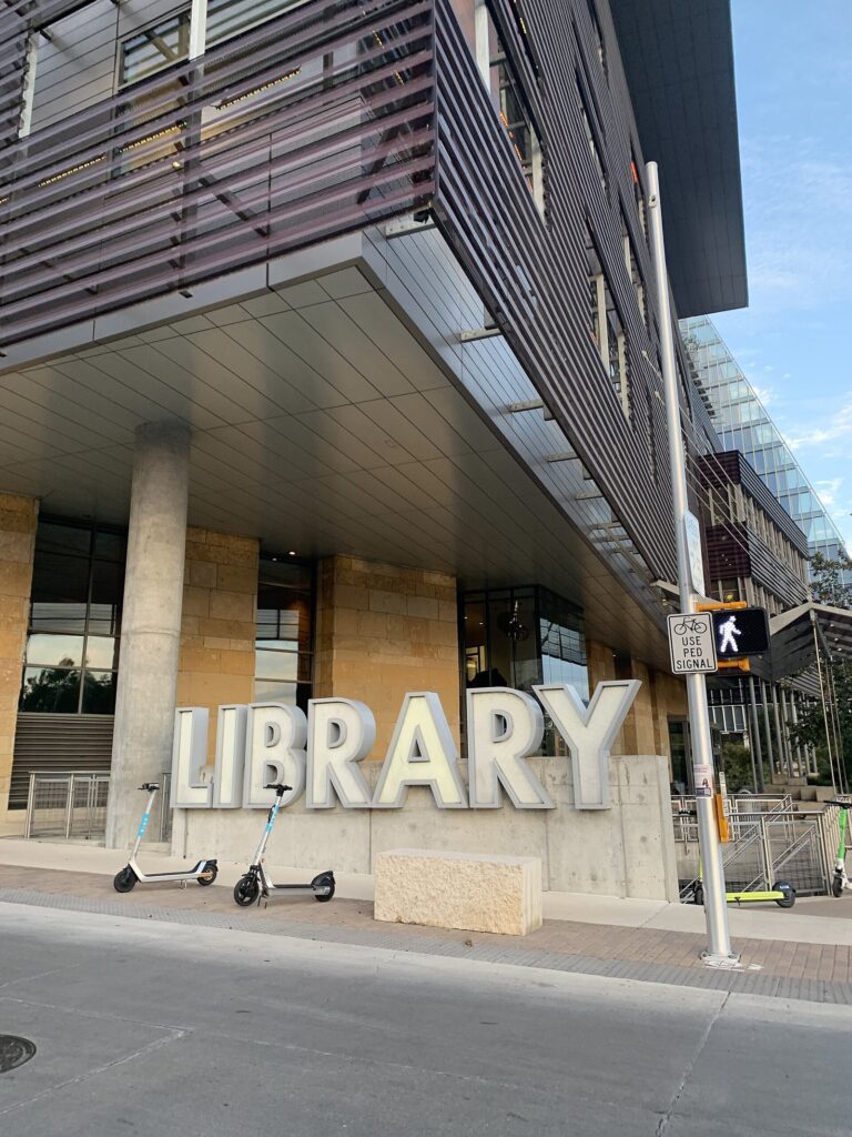 The modern Austin Central Library, a free stop for anyone doing Austin on a budget, with large LIBRARY letters on the sidewalk under its cantilevered upper floors