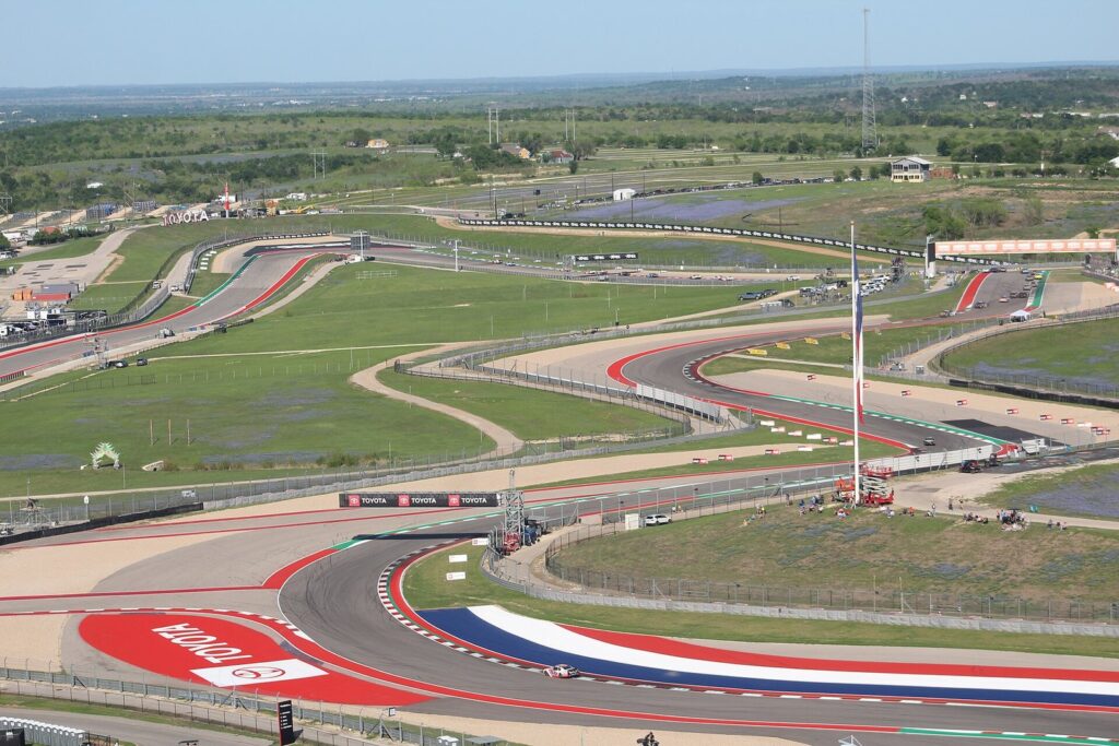 The Circuit of The Americas racetrack winding through open grassland southeast of Austin, with red and white curbs in the foreground