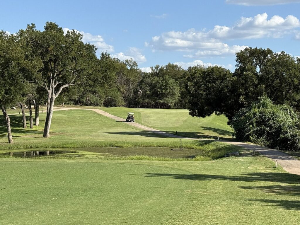 The tree-lined 16th fairway at Lions Municipal Golf Course in Austin, with a pond and green beyond