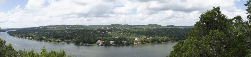 Panoramic view from Mount Bonnell over the blue curve of Lake Austin and the wooded hills and houses along its far shore