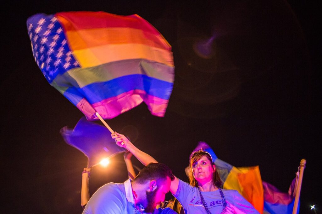 Marchers waving rainbow Pride flags under bright lights during Austin's 2017 Pride Parade, a highlight of any LGBTQ Austin travel guide