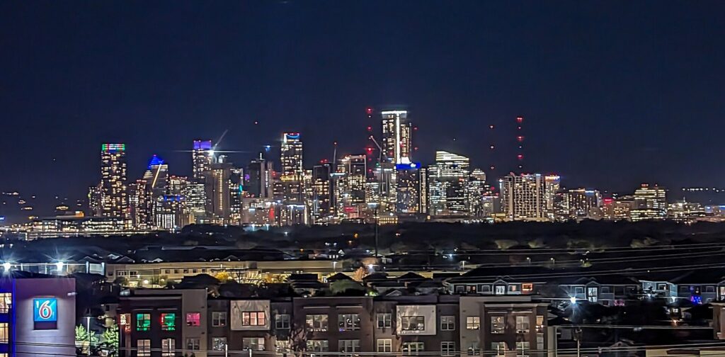 The downtown Austin skyline lit up at night, seen from the east across rooftops