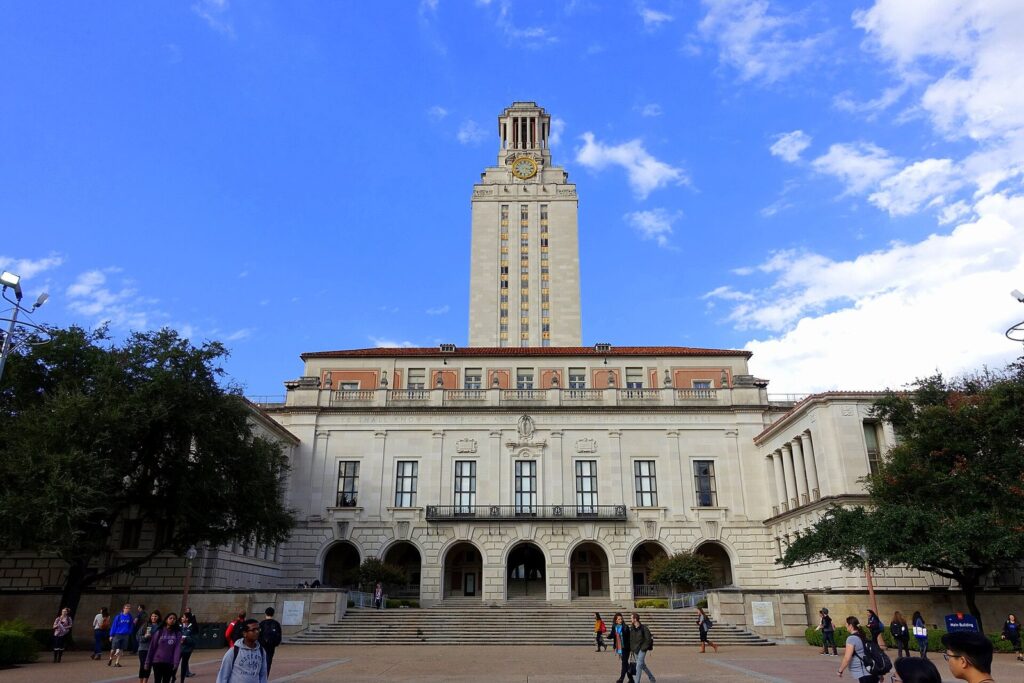 The University of Texas at Austin Main Building and its tall limestone tower rising above the South Mall, with students on the steps