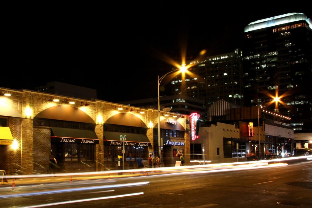 The Warehouse District in downtown Austin at night, with lit brick storefronts and streaks of car lights