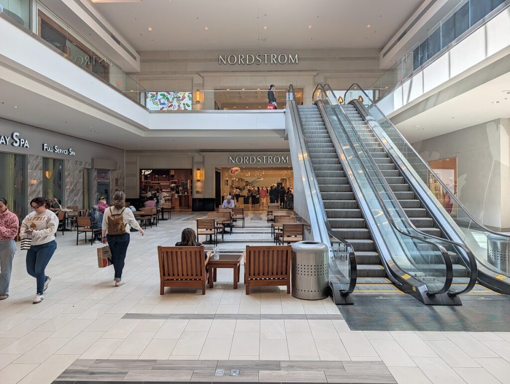 Escalators and a seating area in front of the Nordstrom entrance inside Barton Creek Square mall