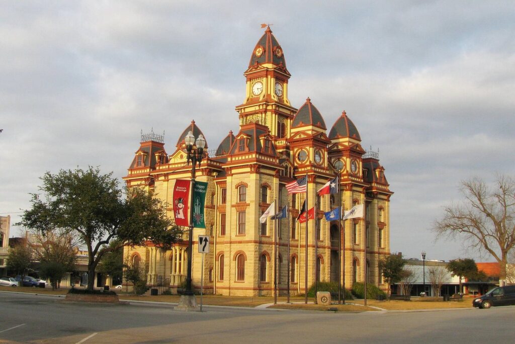 The ornate yellow Caldwell County Courthouse with red domes and a clock tower in Lockhart, Texas, at golden hour