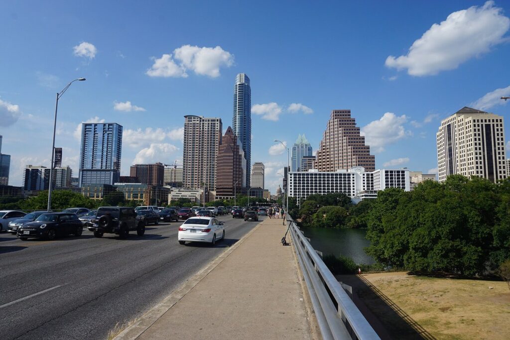 The sidewalk on the Congress Avenue Bridge leading north toward downtown Austin's towers on a sunny day