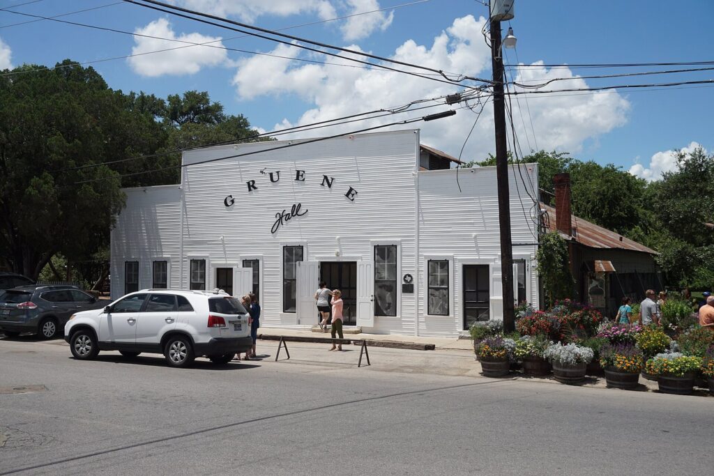 The white clapboard front of Gruene Hall in the Gruene district of New Braunfels, with its painted name and flowers outside