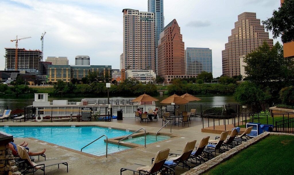 The Hyatt Regency Austin's pool deck with lounge chairs and umbrellas, with downtown towers across Lady Bird Lake