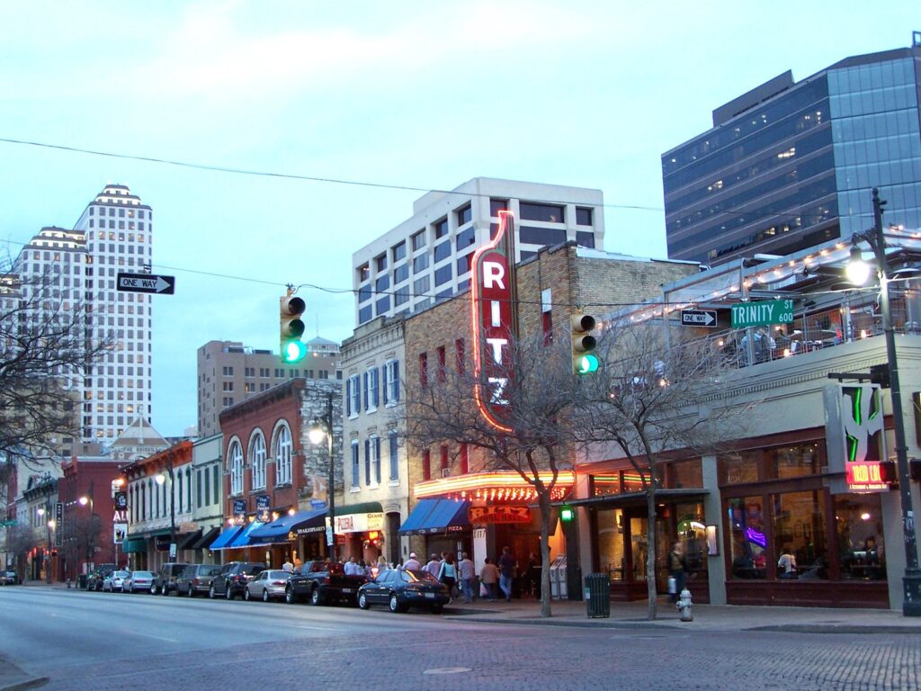 Sixth Street in downtown Austin at dusk, with the neon Ritz sign and historic brick storefronts