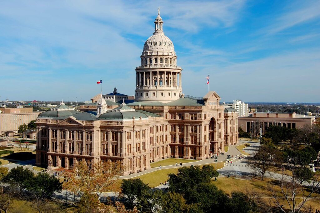 Texas State Capitol dome in sunset-red granite under a blue sky, the first stop in most Austin itineraries