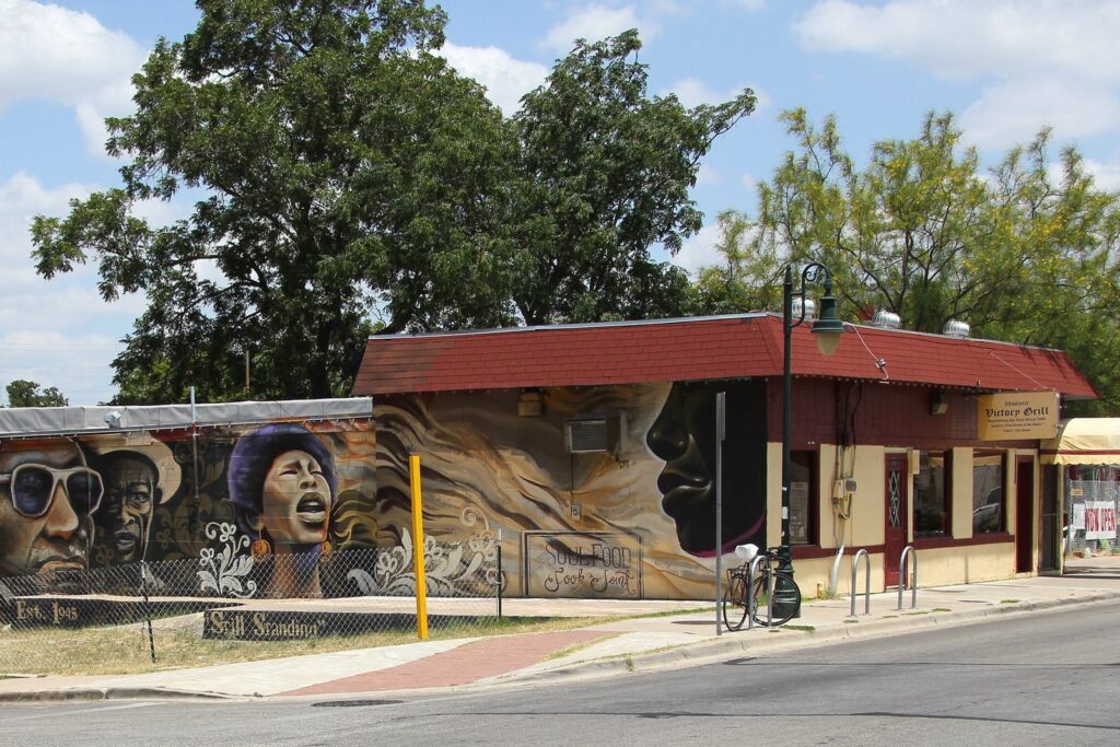 The Victory Grill in East Austin, a low red-roofed building with painted portraits of musicians on an outside wall